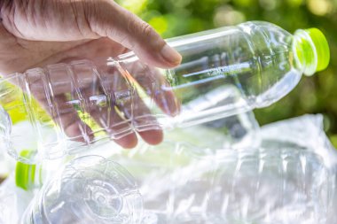 Plastik atık, boş bir plastik şişeyi tutan, plastik atık sorununu sembolize eden, atık yönetimi çabaları ve plastik atıkların azaltılmasına yönelik farkındalık
