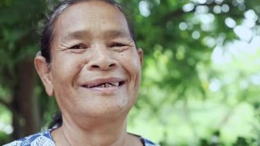 Elderly woman face Happy and Smiled slightly, Portrait elder with facial expression, Close-up portrait grandmother smiling happily on nature garden background, Thai asian