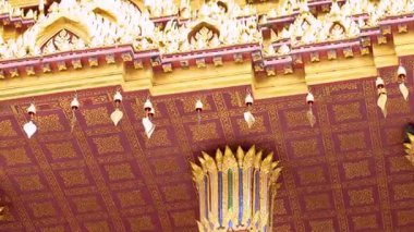 Public Thai temple, Pagoda roof with golden architecture under blue sky, representing traditional cultural heritage and public religious art in Thailand