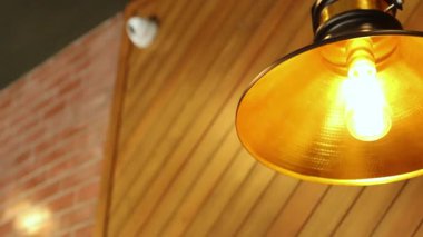 Golden vintage pendant lamp with glowing filament bulb on wooden ceiling, creating warm and stylish interior decoration atmosphere