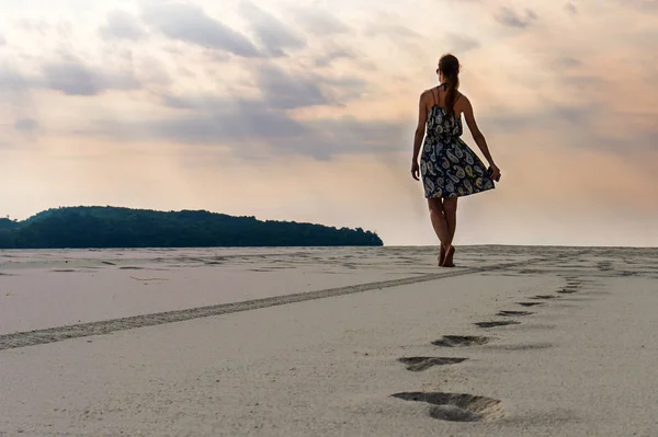 Mulher caminha na praia de areia em direção ao oceano — Fotografia de Stock