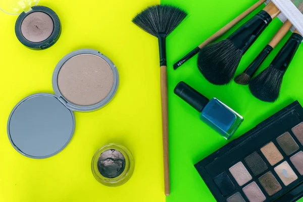 Set cosmetics makeup, brush, eye shadow on yellow-green colorful background.