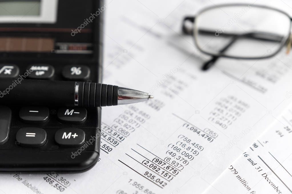 Investment and Financial statement sheet analysis and reporting concept with Calculator, glass and pen. focus selective.