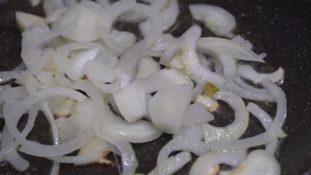 Chefs mano revolviendo cebollas con una espátula en una sartén antiadherente con aceite — Vídeos de Stock