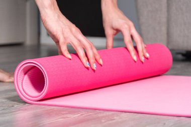 Oturma odasında spor yaptıktan sonra yoga ya da spor salonu paspası katlayan çekici genç bir kadın. Sağlıklı yaşam, sağlıklı kavramları koru.