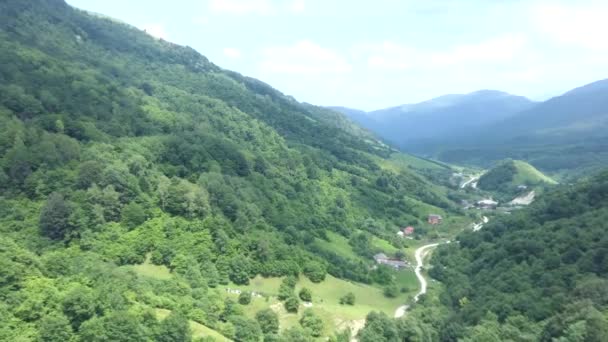 Vídeo aéreo de voar um drone sobre uma pequena aldeia na floresta de alta montanha . — Vídeo de Stock