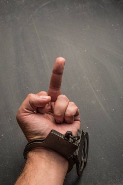 Yandan yakın kadar orta parmak ile koyu arka plan üzerinde kelepçe
