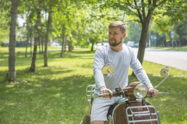Mutlu genç adam Park retro scooter üzerinde oturmuş sakallı