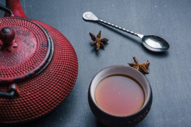 Kırmızı Çaydanlık ve metal kaşık ve siyah çay ile Yıldız anason koyu arka plan.