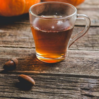 Şükran veya halloween kavramı bir pumpkins, bir cam bardak çay ve meşe palamutları ahşap bir tablo için sonbahar arka plan
