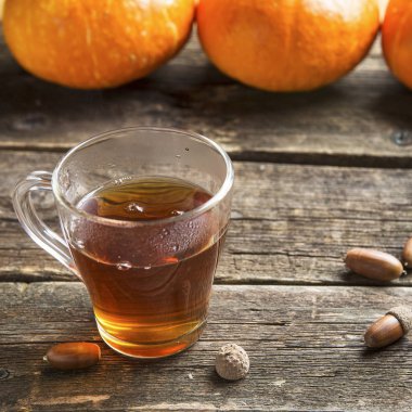 Şükran veya halloween kavramı bir pumpkins, bir cam bardak çay ve meşe palamutları ahşap bir tablo için sonbahar arka plan