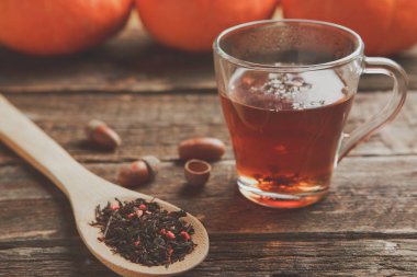 teaand meşe palamutları ve berry bitkisel çay eski ahşap masa üstünde tahta kaşık ile cam fincan