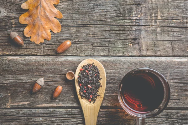 Sonbahar kompozisyon. Bir fincan çay, sonbahar yaprakları ve meşe palamudu. eski ahşap tablo.