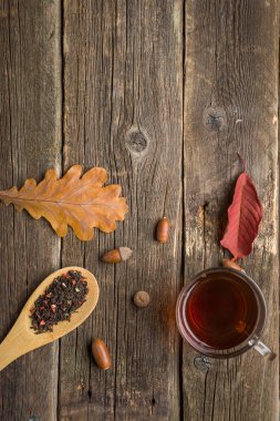 Yaprak, meşe palamudu ve ahşap masa kaşık kuru bitkisel çay ile sonbahar kompozisyon. Tonda fotoğraf