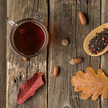 Yaprak, meşe palamudu ve ahşap masa kaşık kuru bitkisel çay ile sonbahar kompozisyon. Tonda fotoğraf