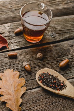 Yaprak, meşe palamudu ve ahşap masa kaşık kuru bitkisel çay ile sonbahar kompozisyon. Tonda fotoğraf