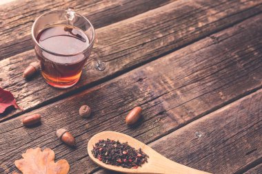 Sonbahar ile çay yaprakları, meşe palamudu ve ahşap masa kaşık kuru bitkisel çay. Tonda fotoğraf