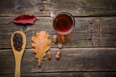 Sonbahar ile çay yaprakları, meşe palamudu ve ahşap masa kaşık kuru bitkisel çay. Tonda fotoğraf