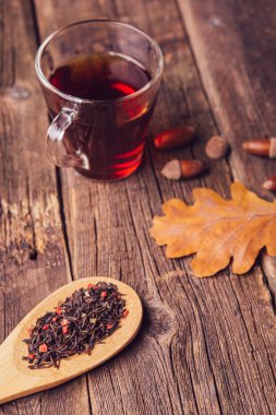 Sonbahar ile çay yaprakları, meşe palamudu ve ahşap masa kaşık kuru bitkisel çay. Tonda fotoğraf