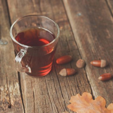 Sonbahar ile çay yaprakları, meşe palamudu ve ahşap masa kaşık kuru bitkisel çay. Tonda fotoğraf