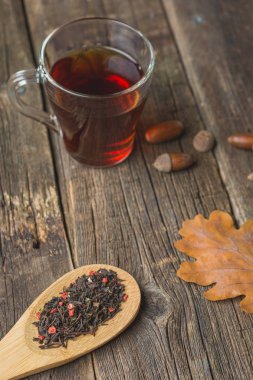 Sonbahar ile çay yaprakları, meşe palamudu ve ahşap masa kaşık kuru bitkisel çay. Tonda fotoğraf