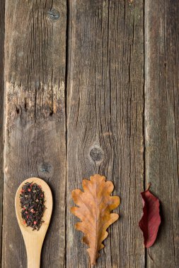 Sonbahar ile çay yaprakları, meşe palamudu ve ahşap masa kaşık kuru bitkisel çay. Tonda fotoğraf