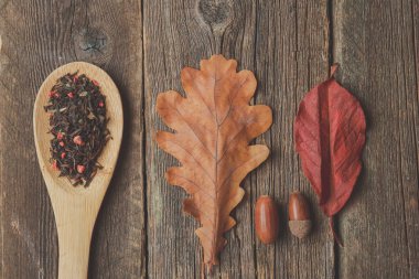 Sonbahar ile çay yaprakları, meşe palamudu ve ahşap masa kaşık kuru bitkisel çay. Tonda fotoğraf