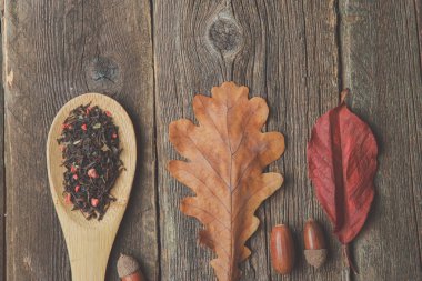 Sonbahar ile çay yaprakları, meşe palamudu ve ahşap masa kaşık kuru bitkisel çay. Tonda fotoğraf