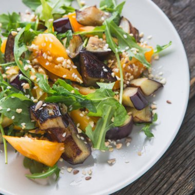 Kaşığı baharat sağlıklı taze salata fırında patlıcan, biber, roka ve taze turuncu domates ile yakın için otlar.