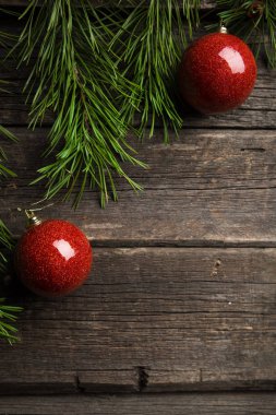 Noel tebrik kartı çerçeve metin için yer ile. Dekorasyon kahverengi eski yıpranmış ahşap Komiteler çerçevede bir yeşil çam dalları, kırmızı cam Noel topları