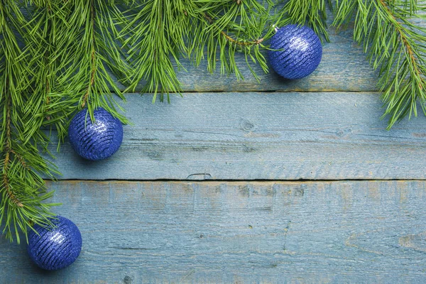 Christmas decoration blue balls with green fir branch on old blue wooden background
