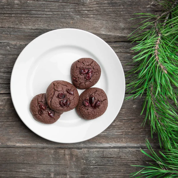 古い木製のボードにクランベリーとモミの枝を持つチョコレート クッキーとクリスマスの背景 — ストック写真