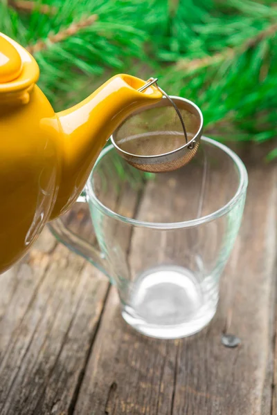 Gelbe Teekanne Gießt Schwarzen Tee Glasschale Auf Holztischhintergrund Mit Tannenzweig — Stockfoto