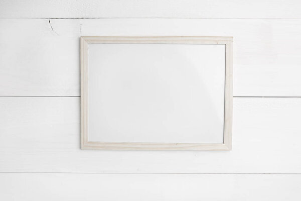 Small empty wooden frame on white wooden background