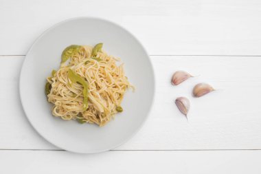 Tabakta biber ve beyaz ahşap arka plan üzerinde sarımsak karanfil ile Erişte