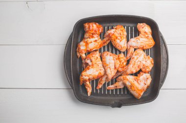 Baharat ve yalan bir siyah dökme demir tavada Beyaz ahşap bir masa üzerinde Marine çiğ tavuk kanadı