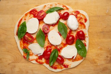 Kesme tahtası üst görünümünde pişmemiş ev yapımı pizza