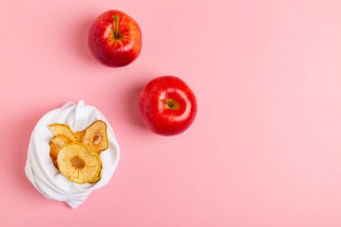 Ev yapımı güneşte kurutulmuş organik elma dilimleri, gevrek elma cipsi, taze elma ile pembe arka plan üzerinde.