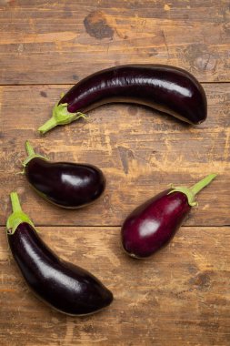 Koyu rustik ahşap arka plan üzerinde taze topalmış çiğ patlıcan