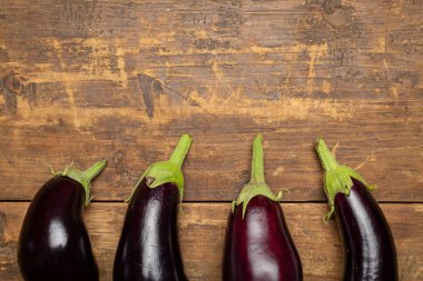 Koyu rustik ahşap arka plan üzerinde taze topalmış çiğ patlıcan