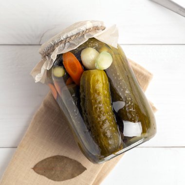 Beyaz arka planda salatalık turşulu cam kavanoz.