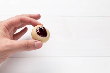 Beyaz arka planda elinde böğürtlenli kurabiye var..