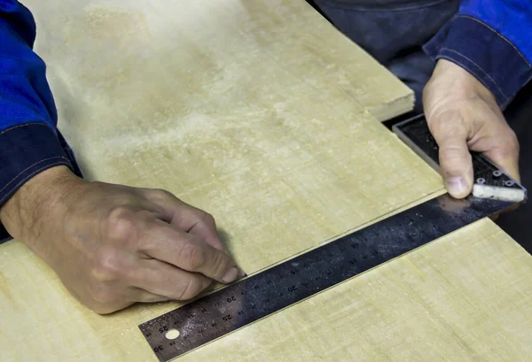 a carpenter draws a line measuring it with a corner