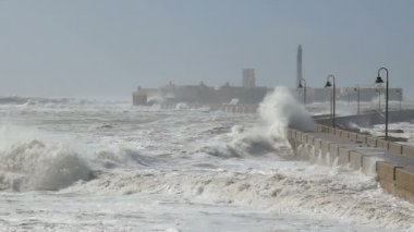Güçlü dönen okyanus akıntıları ve Cadiz deniz kenarındaki sete üst üzerinde püskürtme dalgalar gösteren ağır çekim klibi.