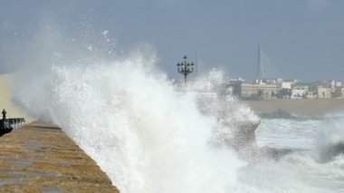 Deniz kenarındaki sete Cadiz İspanya, okyanus sprey büyük bir bulutu yapma isabet devasa bir dalga yavaş çekim kapatın.