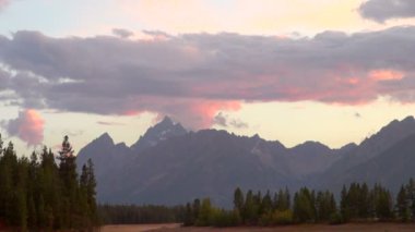 Zaman atlamalı gri bulutların üstünde tepe-in çok yüksek dağların Grand Teton Milli Parkı, hareket