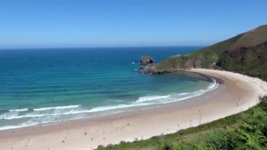 Pan tüm kabuk güzel Torimbia Beach parlak güneşli bir günde şeklinde yakalama vurdu. Turistler tüm kıyı ve dalgalar keyfini sörfçüler dotting görülür.