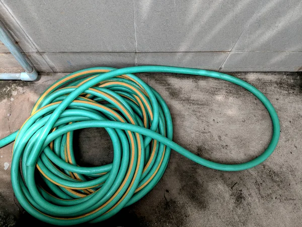 green rubber hose on the floor near the faucet