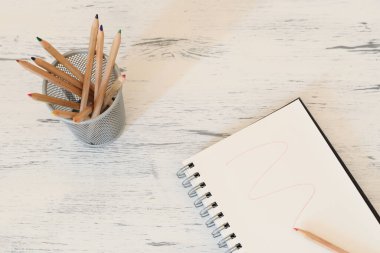 Renkli kalemlerle dolu bir kalem kutusu ve kırmızı bir iz bırakan bir defter.