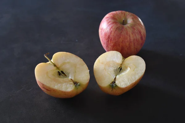 Apple cut in two halves and a full apple over a blackboard background
